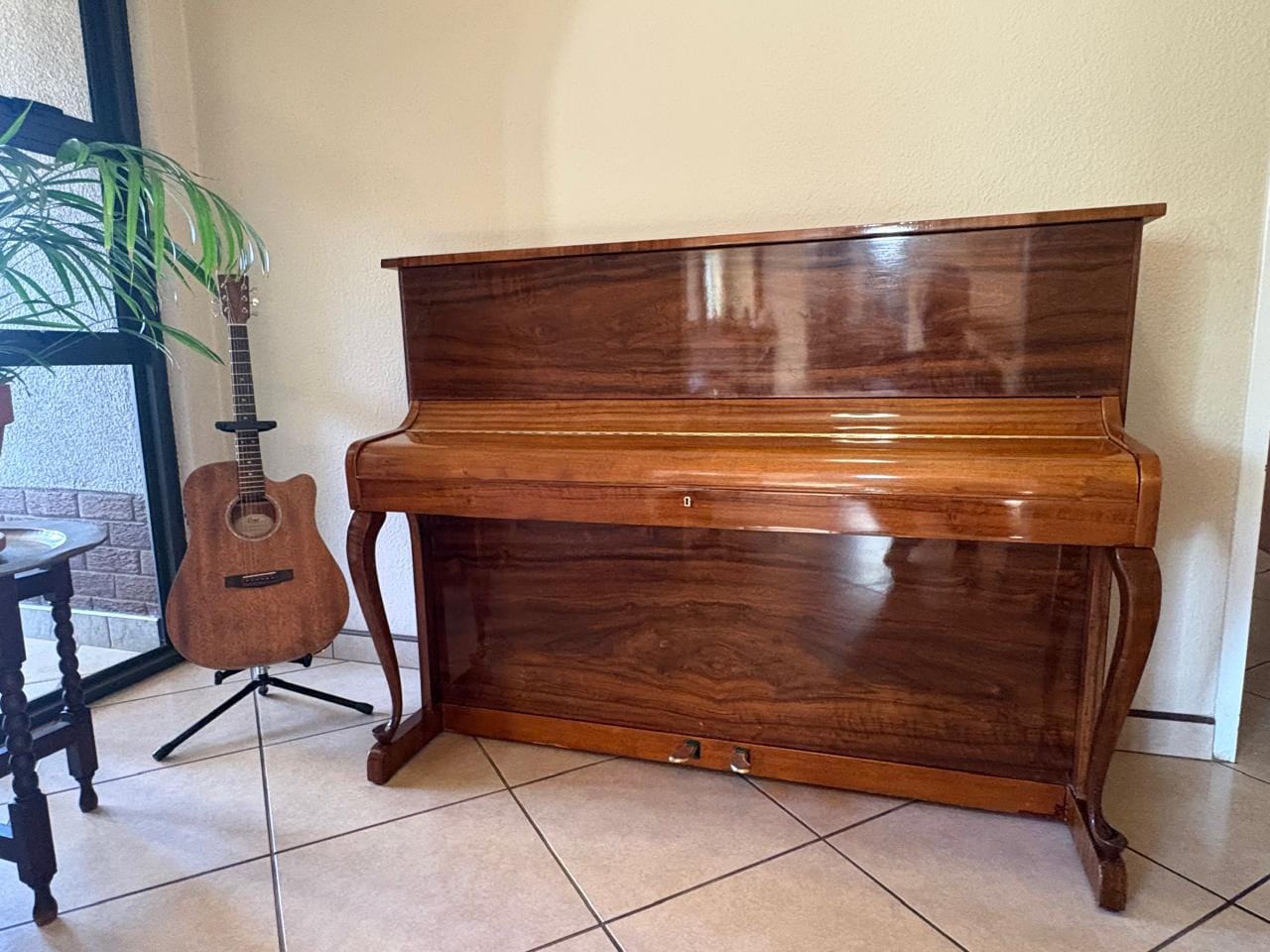 A restored walnut upright piano standing in a customer's home