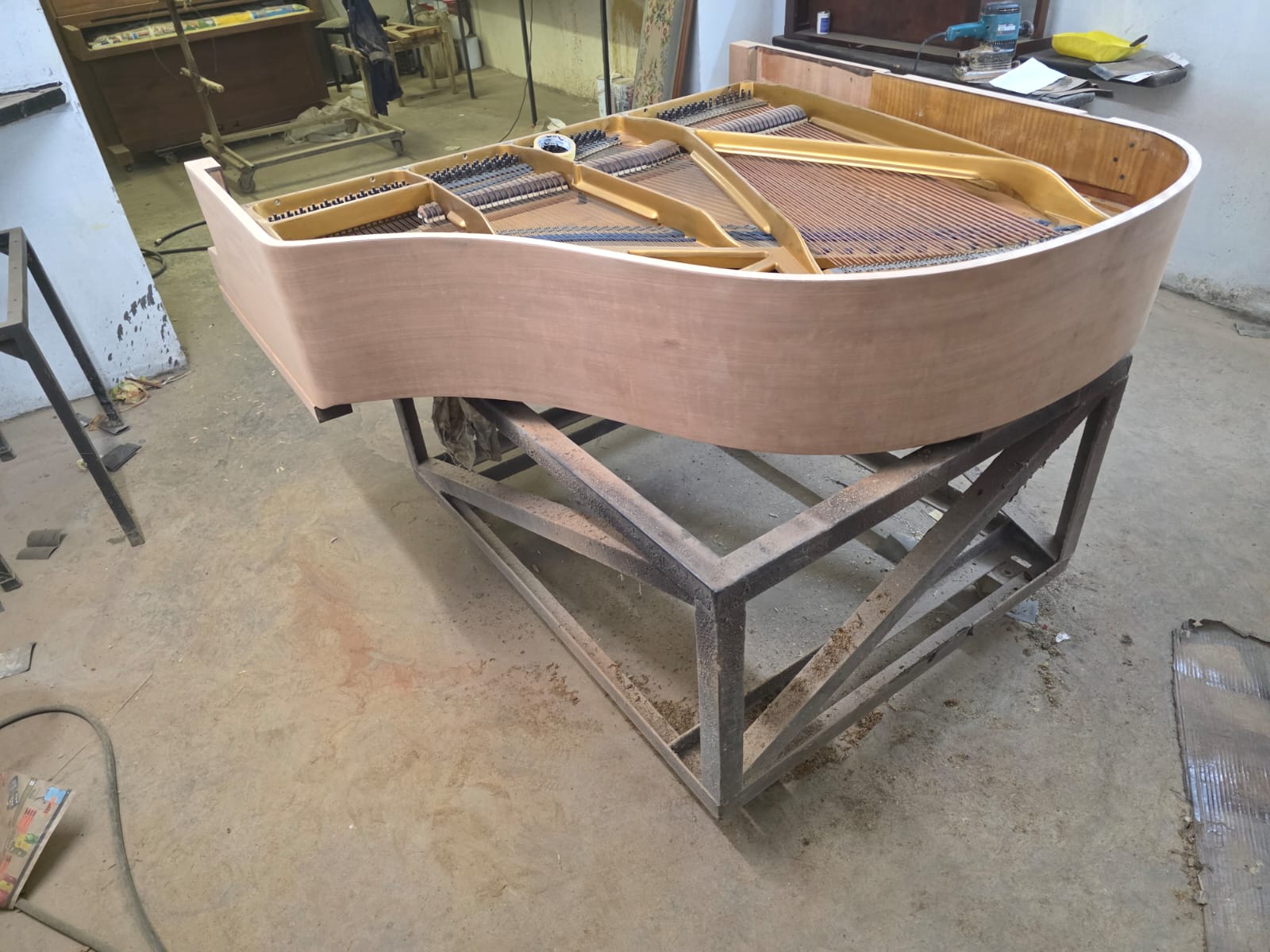 A bare wooden grand piano rim before the new finish is applied
