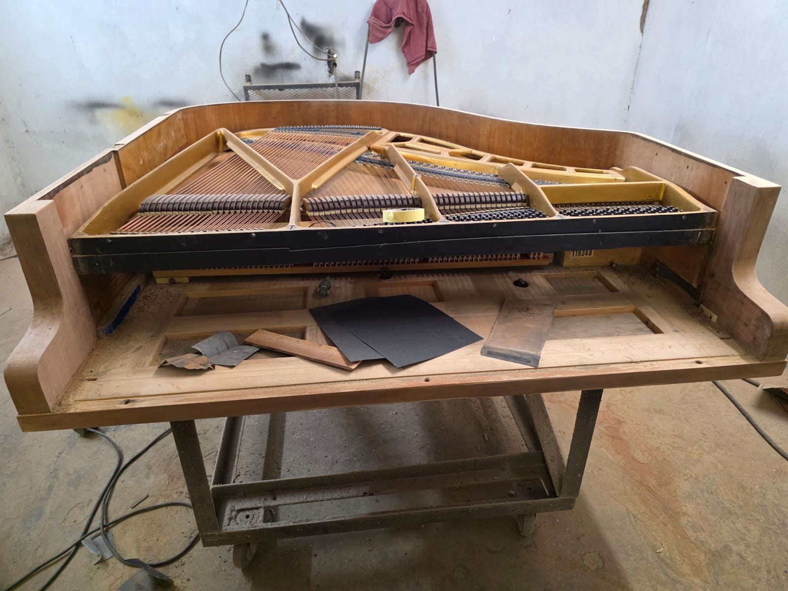 A stripped baby grand cabinet on the workshop trolley, ready for sanding
