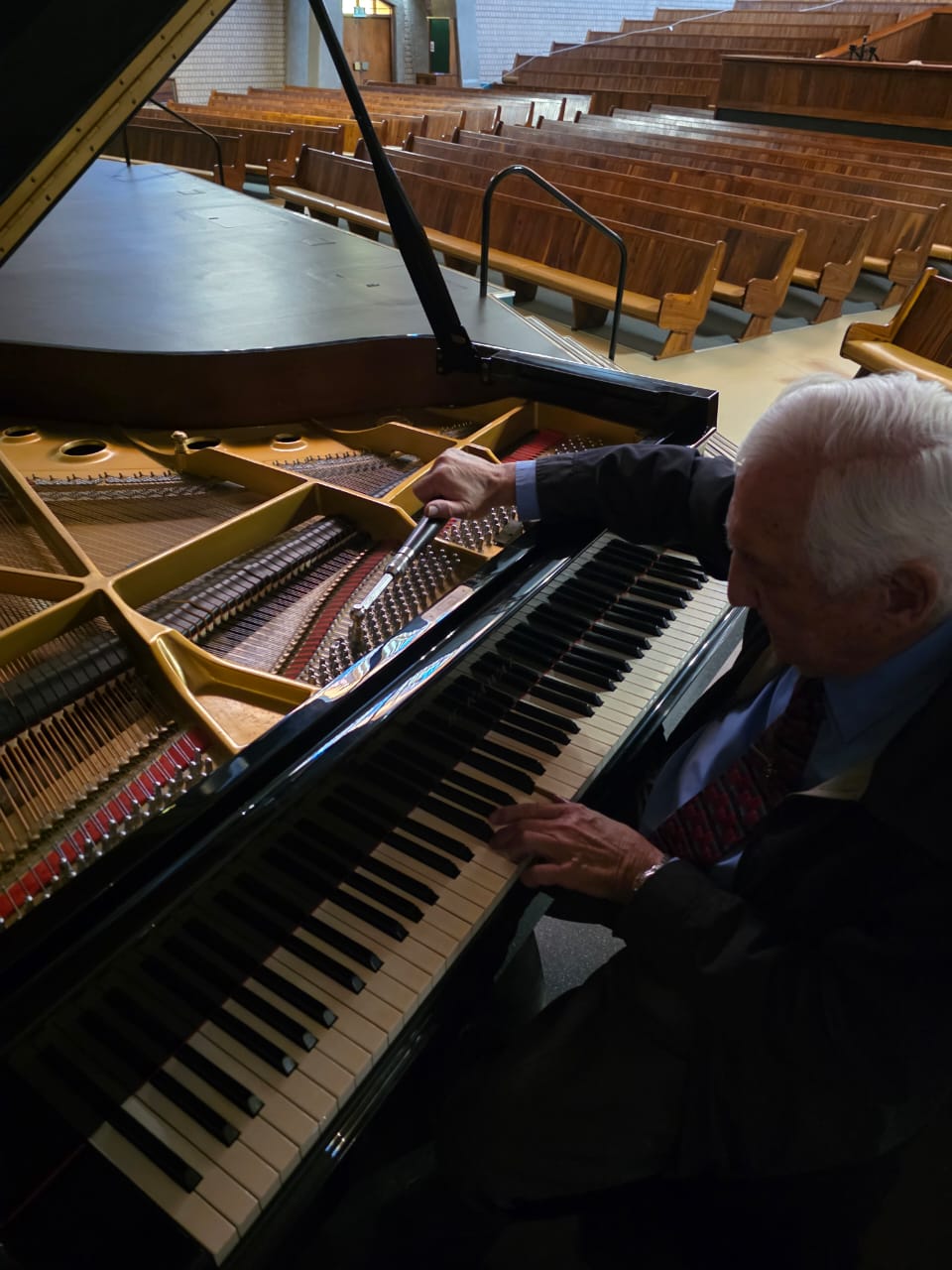 Bennie Dekker tuning the strings and pins of a grand piano